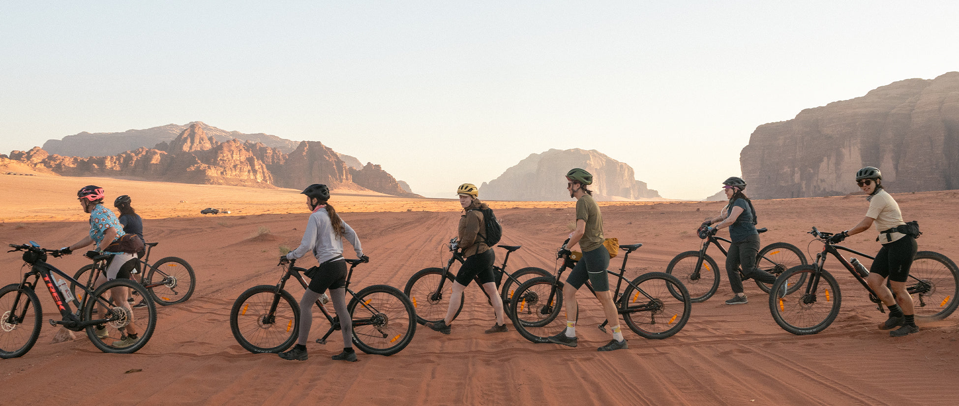 A group of women walking bikes across a desert