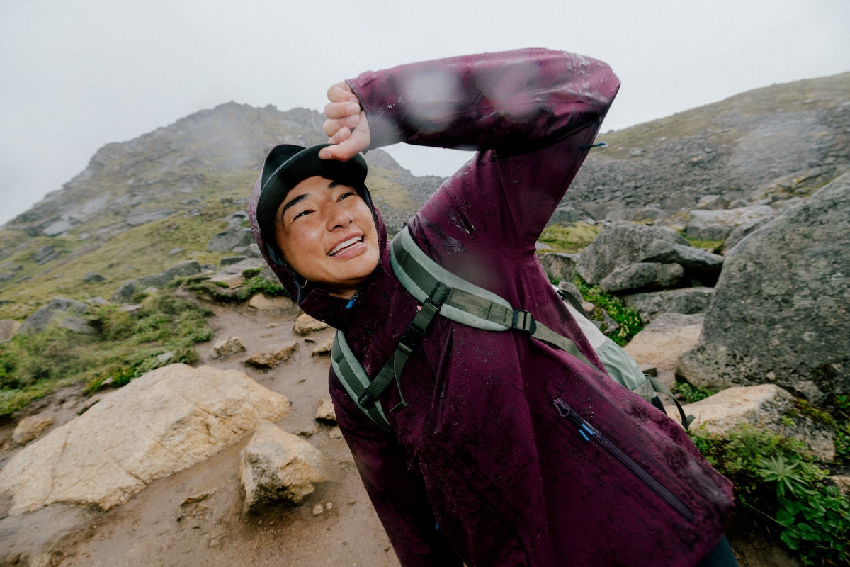 A woman smiling in the rain with her hood up