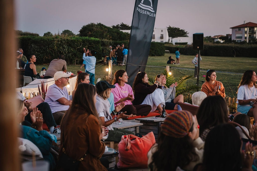 People sat around on deck chairs as the sun starts to set, applauding